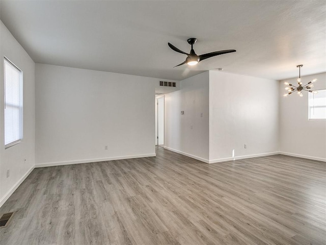 spare room with light hardwood / wood-style flooring and ceiling fan with notable chandelier