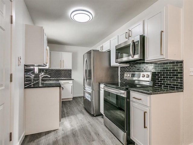 kitchen with light hardwood / wood-style floors, white cabinetry, sink, and appliances with stainless steel finishes