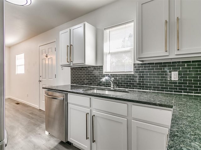 kitchen featuring stainless steel dishwasher, white cabinets, a wealth of natural light, and light hardwood / wood-style flooring