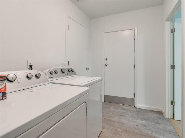 laundry area with washer and dryer and light hardwood / wood-style flooring