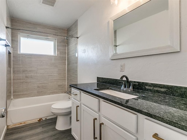 full bathroom with hardwood / wood-style flooring, tiled shower / bath combo, toilet, and vanity