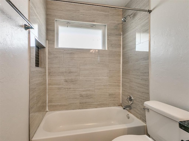 bathroom with tiled shower / bath combo and toilet