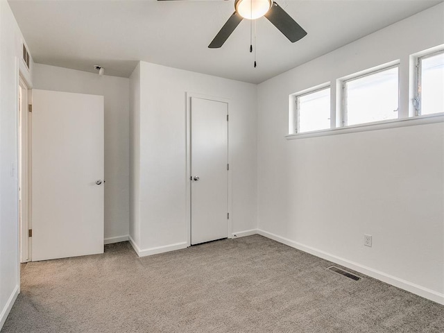 unfurnished bedroom with ceiling fan, a closet, light colored carpet, and multiple windows