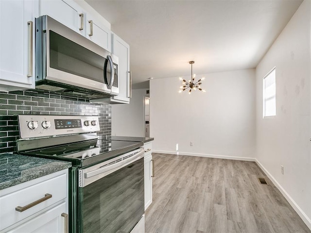 kitchen featuring backsplash, a chandelier, white cabinets, and stainless steel appliances