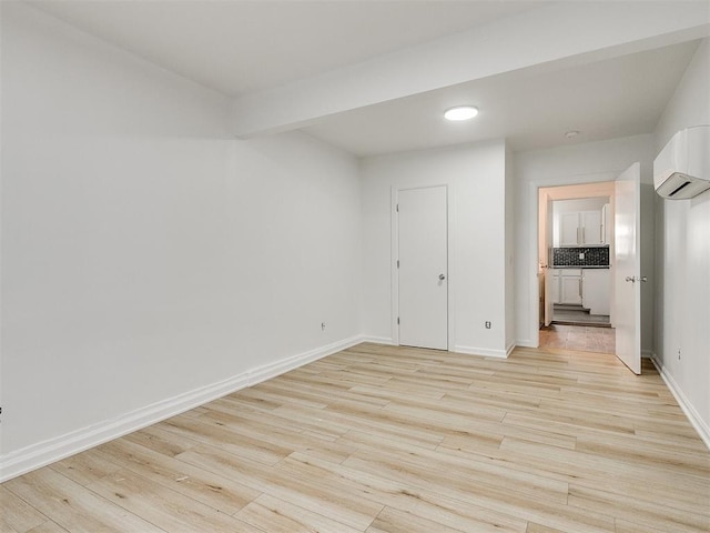 empty room with light hardwood / wood-style flooring and an AC wall unit