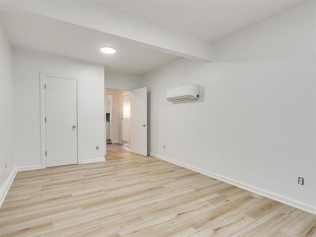 unfurnished room featuring light hardwood / wood-style flooring and a wall mounted air conditioner