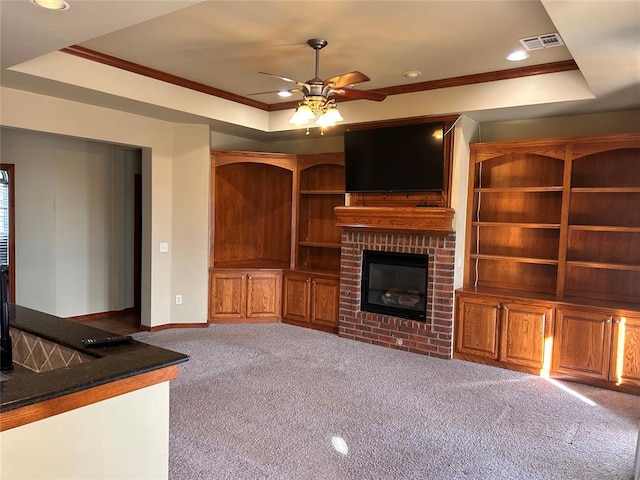 unfurnished living room with a tray ceiling, ceiling fan, light carpet, and a brick fireplace