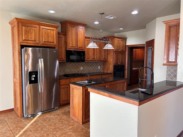 kitchen featuring sink, kitchen peninsula, pendant lighting, decorative backsplash, and black appliances