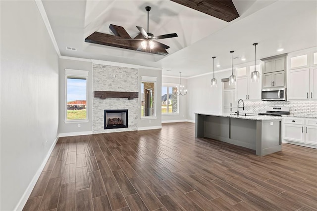 kitchen with pendant lighting, light stone countertops, a center island with sink, and white cabinetry