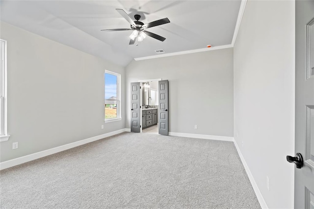 unfurnished bedroom with connected bathroom, ceiling fan, crown molding, lofted ceiling, and light carpet