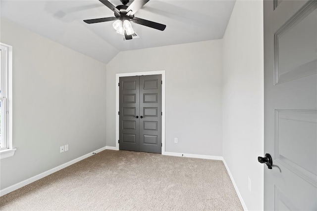 carpeted spare room featuring vaulted ceiling and ceiling fan