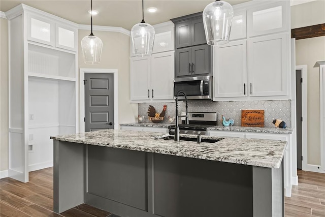 10513 SW 51st St, Mustang, OK 73064 - kitchen with stainless steel microwave, decorative backsplash, wood finished floors, light stone countertops, and white cabinets