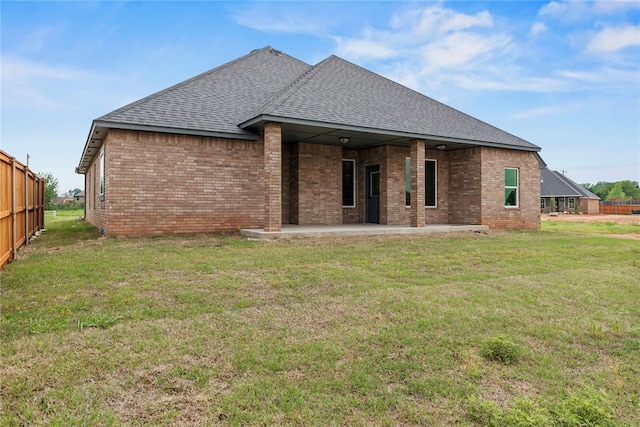 10513 SW 51st St, Mustang, OK 73064 - back of property with roof with shingles, brick siding, a patio, and a lawn