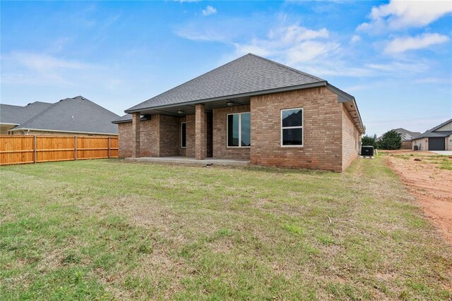 10513 SW 51st St, Mustang, OK 73064 - rear view of property featuring brick siding, a patio, roof with shingles, and central AC unit