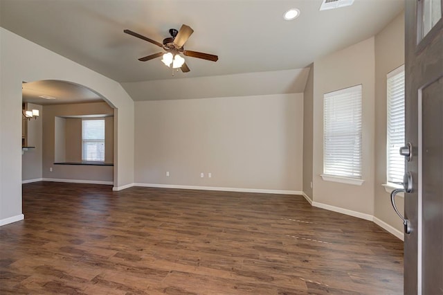 spare room featuring dark hardwood / wood-style flooring, ceiling fan with notable chandelier, lofted ceiling, and a healthy amount of sunlight