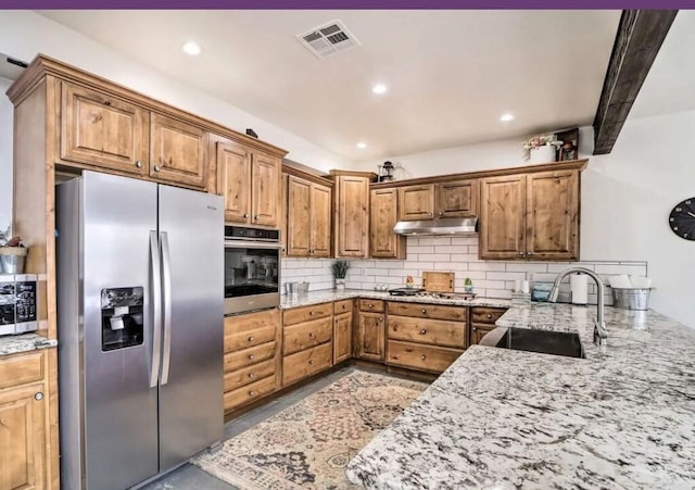 kitchen featuring sink, appliances with stainless steel finishes, tasteful backsplash, light stone counters, and kitchen peninsula