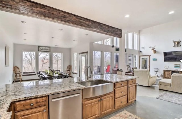 kitchen with stainless steel dishwasher, beam ceiling, light stone countertops, and sink