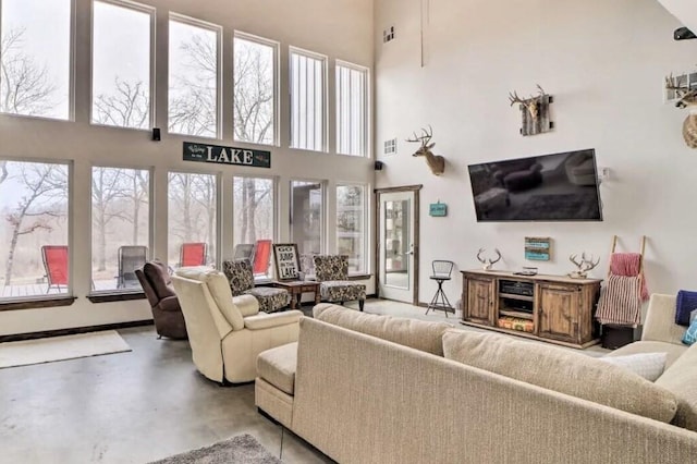 living room featuring a wealth of natural light, a towering ceiling, and concrete floors