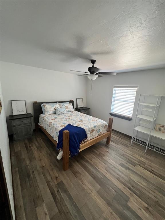 bedroom with a textured ceiling, dark hardwood / wood-style floors, and ceiling fan