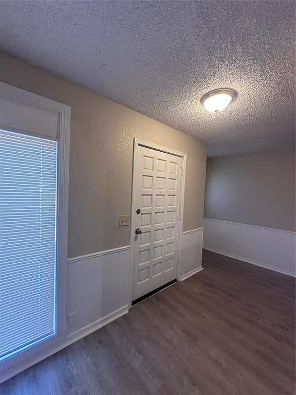 foyer entrance featuring a textured ceiling and dark wood-type flooring