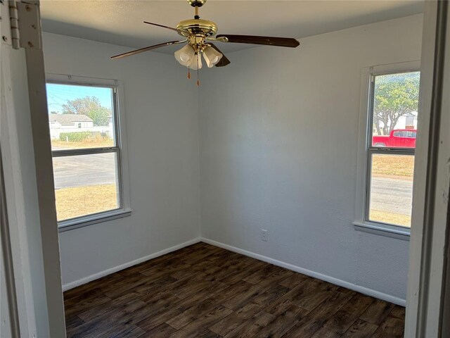 empty room with plenty of natural light, baseboards, and dark wood-style flooring