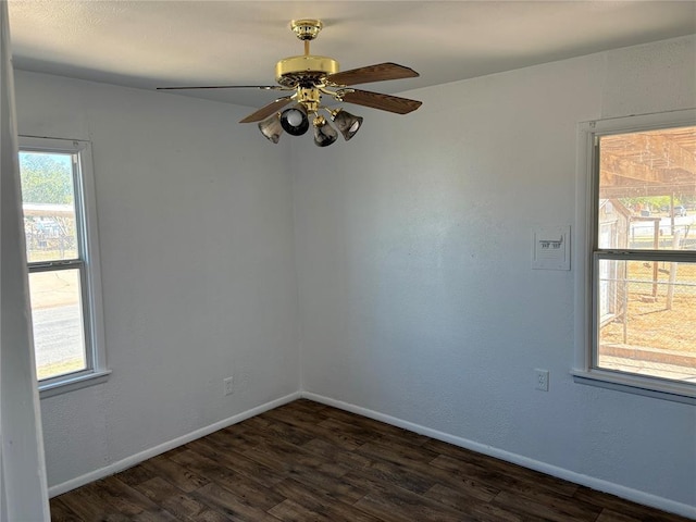 empty room with a ceiling fan, baseboards, and dark wood-type flooring