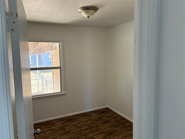 spare room with dark wood finished floors, a textured ceiling, and baseboards