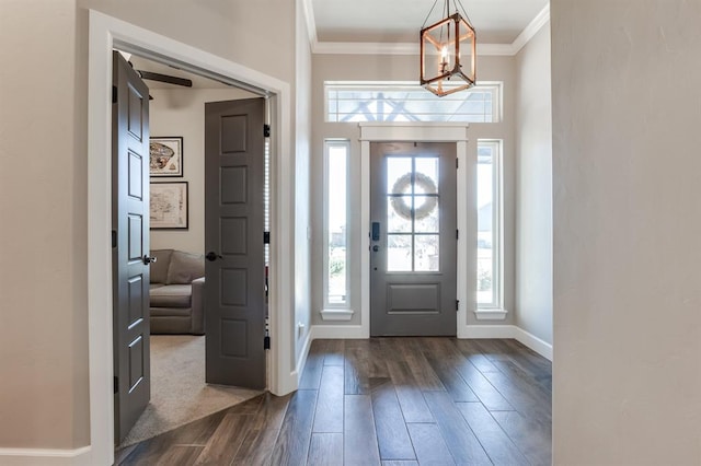 foyer featuring dark hardwood / wood-style flooring, ornamental molding, and an inviting chandelier