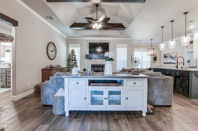 interior space with dark hardwood / wood-style flooring, ceiling fan, decorative light fixtures, white cabinets, and a breakfast bar area