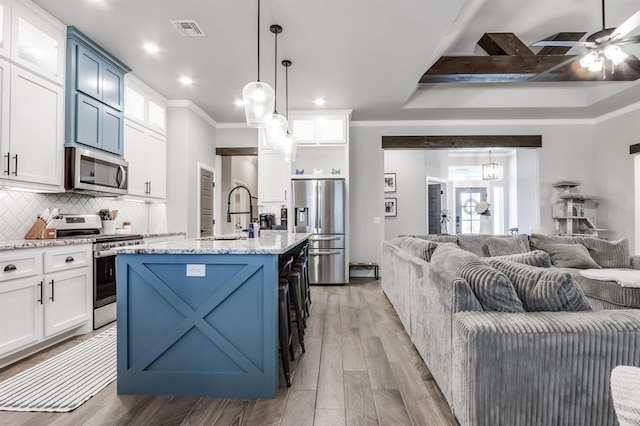 kitchen featuring pendant lighting, a kitchen island with sink, sink, light hardwood / wood-style flooring, and appliances with stainless steel finishes