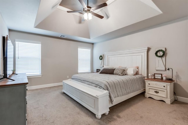 bedroom featuring a raised ceiling, multiple windows, and ceiling fan