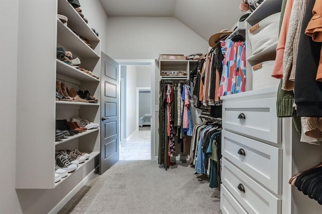 spacious closet with light colored carpet and vaulted ceiling