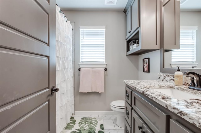 bathroom with vanity, toilet, and plenty of natural light