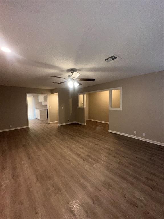 unfurnished living room featuring a textured ceiling, ceiling fan, and dark wood-type flooring