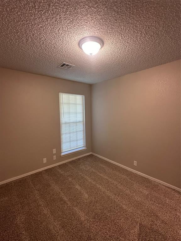 empty room featuring carpet and a textured ceiling