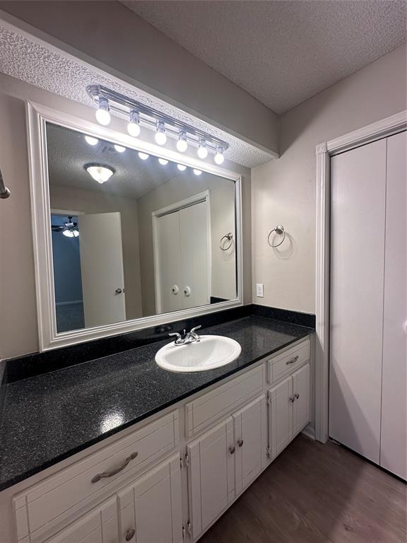 bathroom featuring ceiling fan, vanity, wood-type flooring, and a textured ceiling