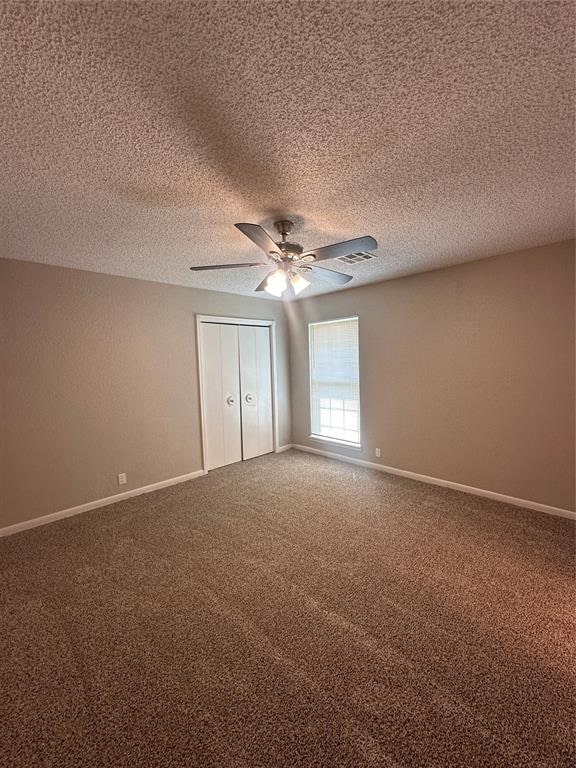 unfurnished bedroom featuring a textured ceiling, a closet, ceiling fan, and carpet floors