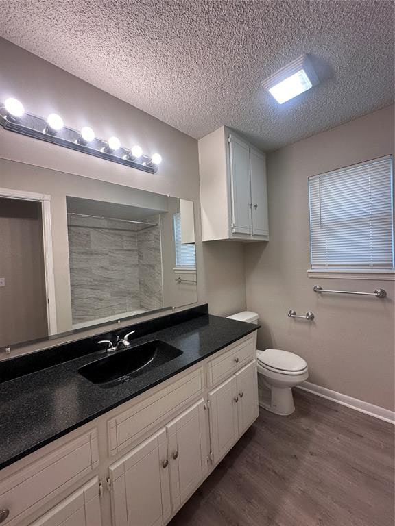 bathroom with a shower, hardwood / wood-style floors, a textured ceiling, toilet, and vanity