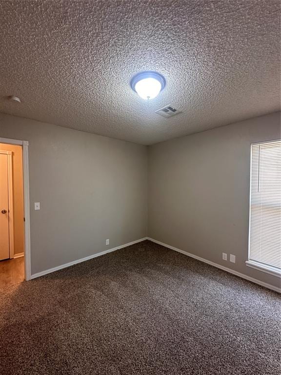 spare room featuring carpet flooring and a textured ceiling