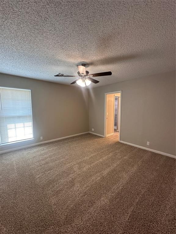 carpeted empty room featuring ceiling fan and a textured ceiling