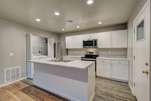 kitchen with a kitchen island with sink, white cabinetry, stainless steel appliances, and light hardwood / wood-style floors