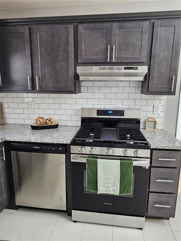 kitchen with light stone counters, dark brown cabinetry, stainless steel appliances, and tasteful backsplash