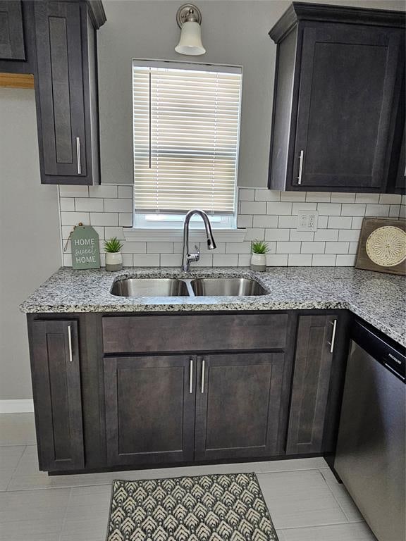 kitchen featuring sink, tasteful backsplash, light stone counters, stainless steel dishwasher, and light tile patterned floors