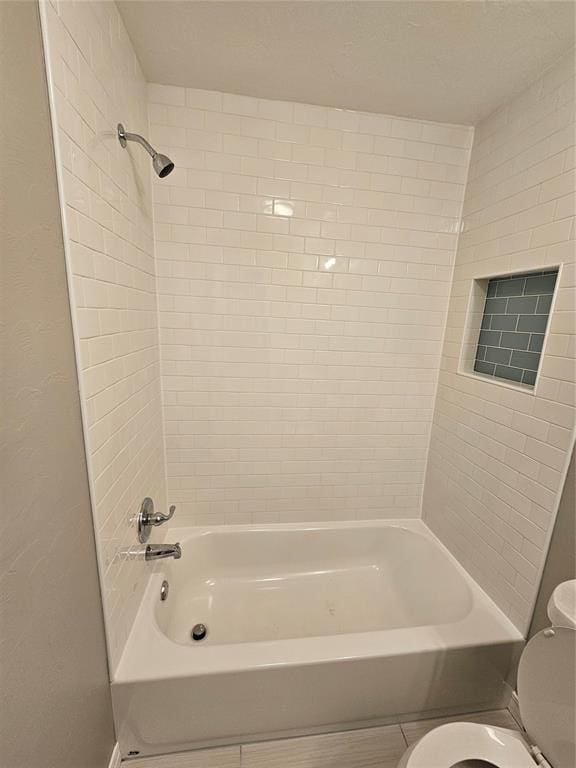 bathroom with toilet and tiled shower / bath