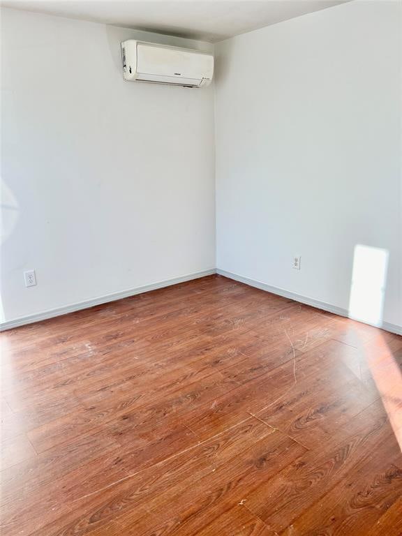 empty room with wood-type flooring and a wall mounted AC