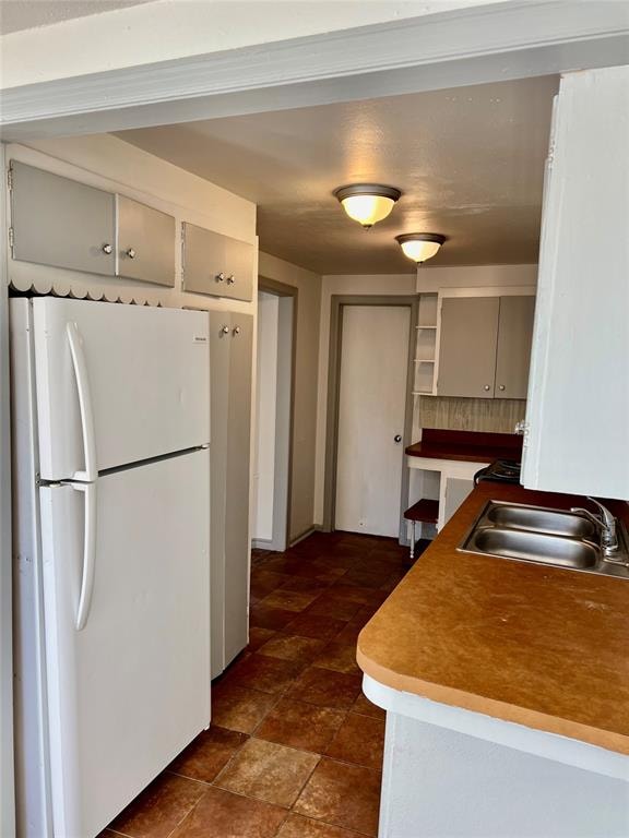 kitchen featuring decorative backsplash, white refrigerator, gray cabinets, and sink