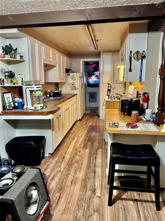 kitchen featuring sink, white cabinets, light hardwood / wood-style floors, and white refrigerator