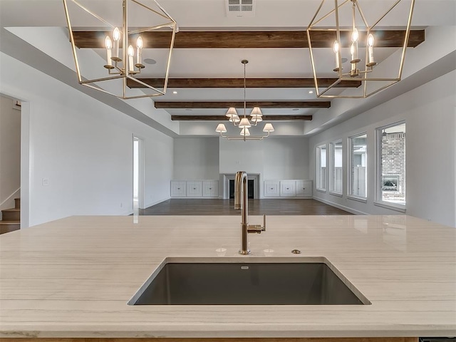 kitchen with pendant lighting, beam ceiling, a chandelier, and sink