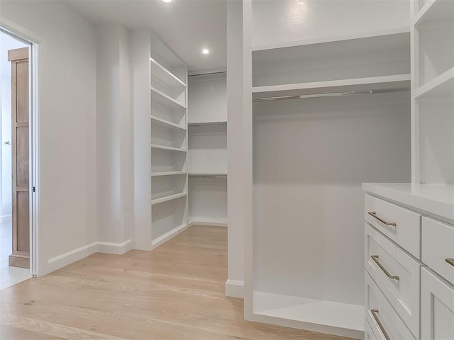 walk in closet with light hardwood / wood-style flooring