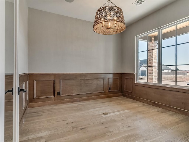 spare room featuring an inviting chandelier and light wood-type flooring